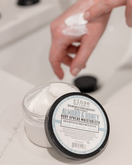 Almond & Honey body spread scooped and worked into skin — warm almond and honey in a rich butter that finishes clean, not greasy. Rinse Bath & Body Co.