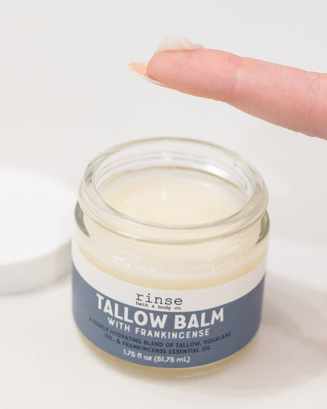 Frankincense tallow balm scooped from the jar, showing its whipped texture — melts on contact and seals moisture in. Rinse Bath & Body Co.