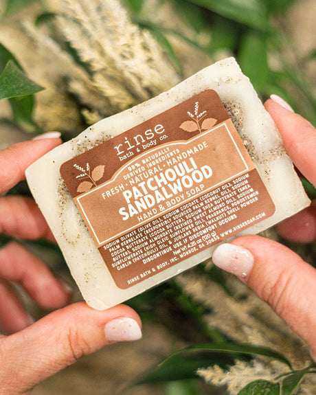 Patchouli Sandalwood bar soap held in hand — deep, grounding woods and resin for an everyday shower. Rinse Bath & Body Co.