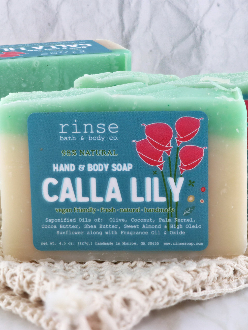 Calla Lily soap rests on white crocheted lace — soft fabric folds and cream teal layers in gentle light