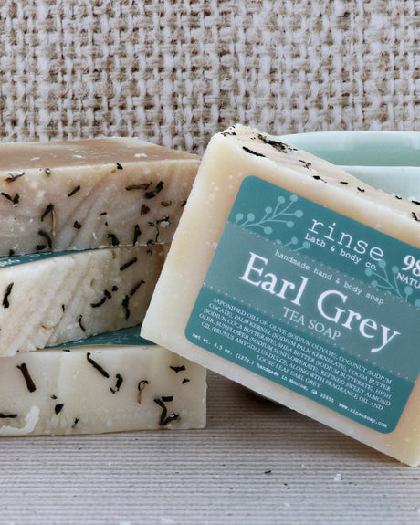 Earl Grey Tea Soap stack on coarse burlap — tea-flecked cream bars with teal label in warm light