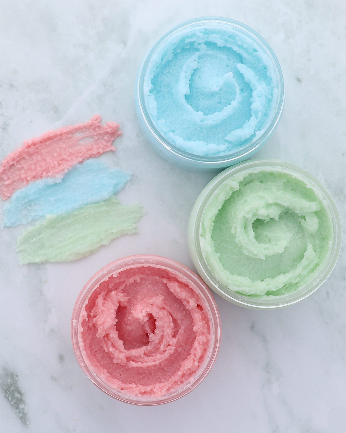 Pomegranate body buff sugar scrub in its tub, showing the sugar grains suspended in oil — scrubs, then turns to lotion in the shower. Rinse Bath & Body Co.
