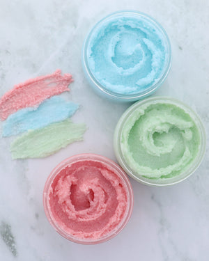 Pomegranate body buff sugar scrub in its tub, showing the sugar grains suspended in oil — scrubs, then turns to lotion in the shower. Rinse Bath & Body Co.