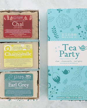 Open Tea Party gift box holding Chai, Chamomile and Earl Grey soaps beside its teal floral sleeve on marble