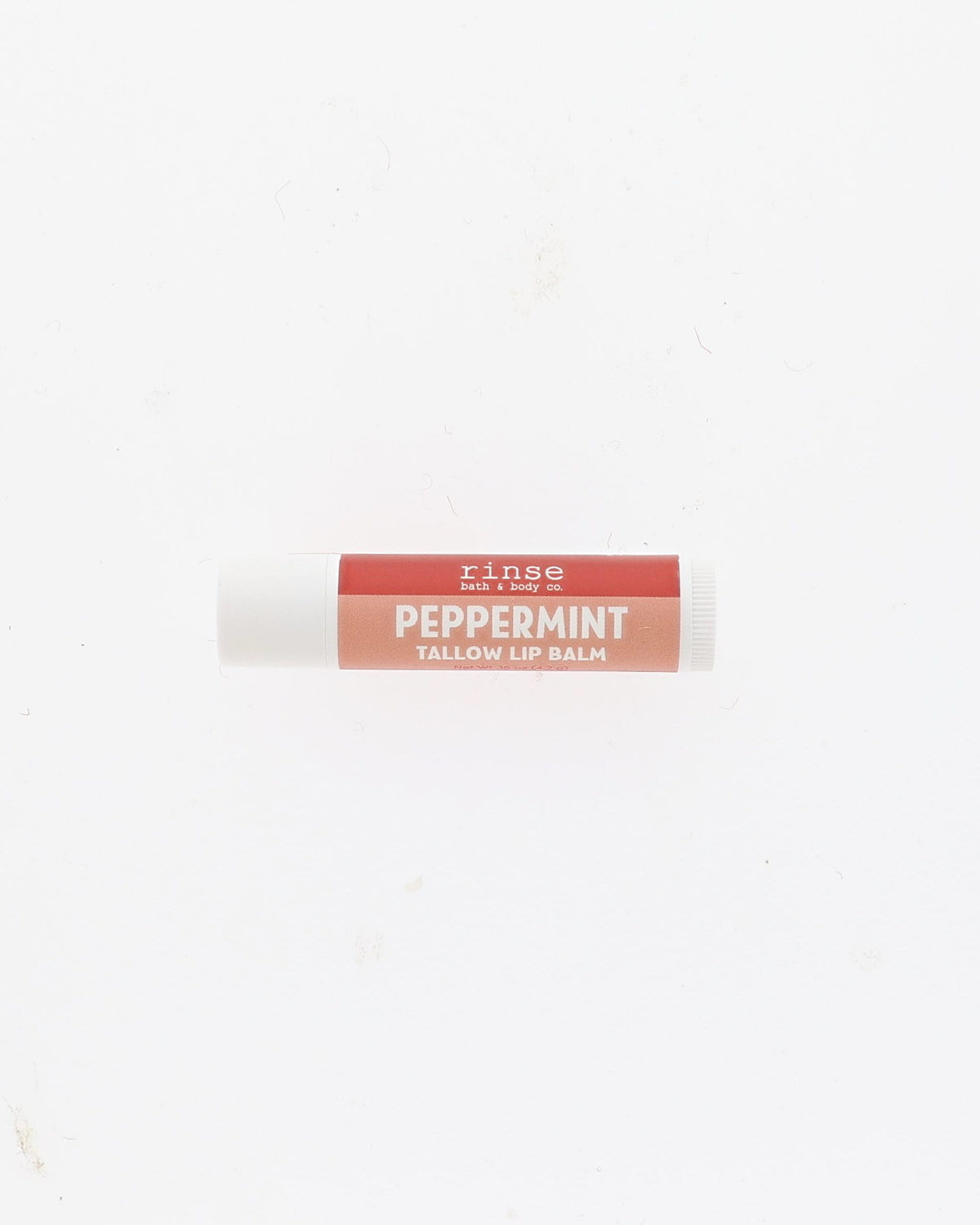 A single tube of Rinse Peppermint Tallow Lip Balm centered on a plain white background.