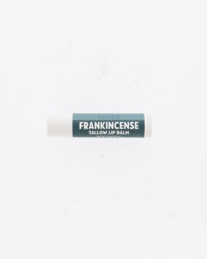Frankincense Tallow Lip Balm tube with deep teal label and white cap lying on a plain white background