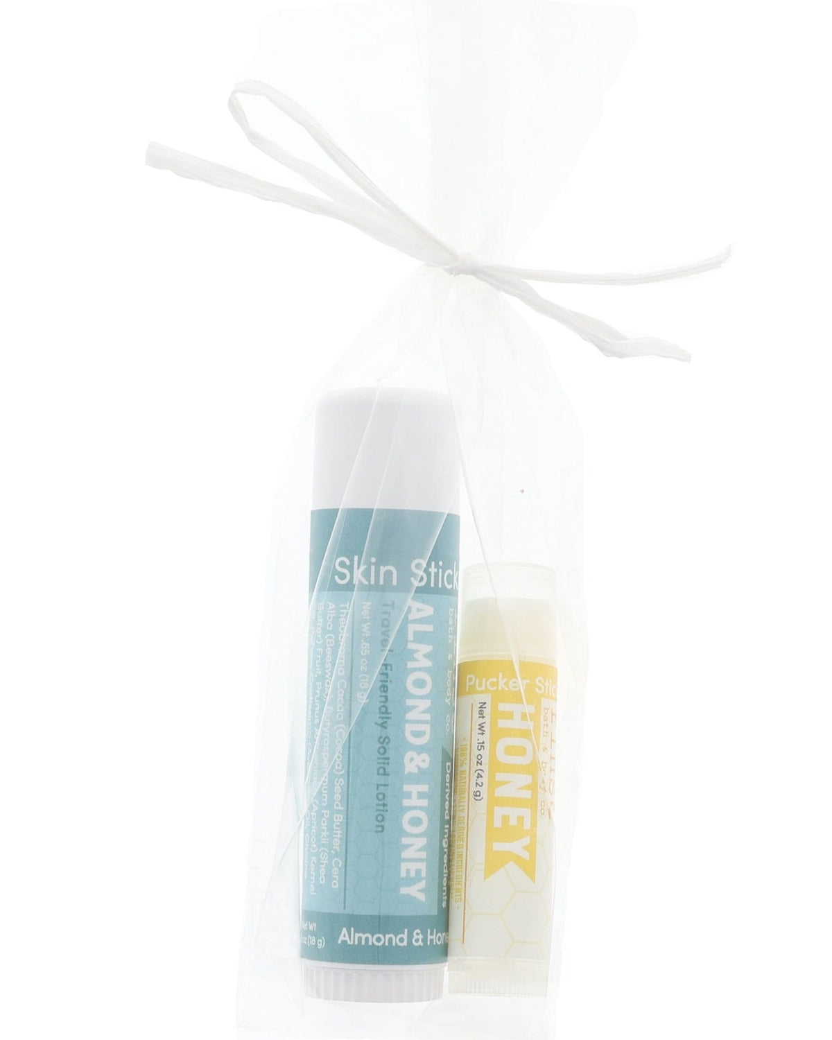 Almond & Honey Skin Stick and Honey Pucker Stick tucked in a sheer white mesh bag — gift-ready duo on bright white