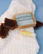 Almond & Honey bar and Honey Pucker Stick resting on a waffle towel with honeycomb — spa-calm blue surface in soft light