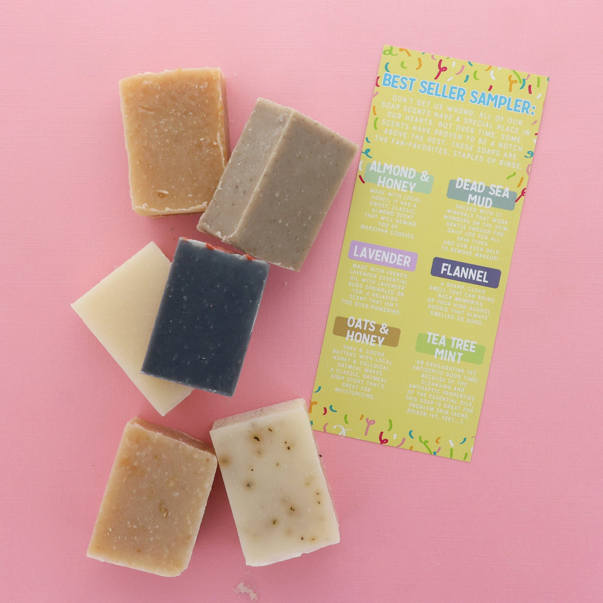 Half-bars lined beside a Best Seller card on hot pink — grainy honey, charcoal mud, and flecked botanical soaps in bright light