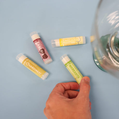 Hand picking Margarita Pucker Stick from Beverage Box set on light blue — Sangria Piña Colada Chardonnay nearby