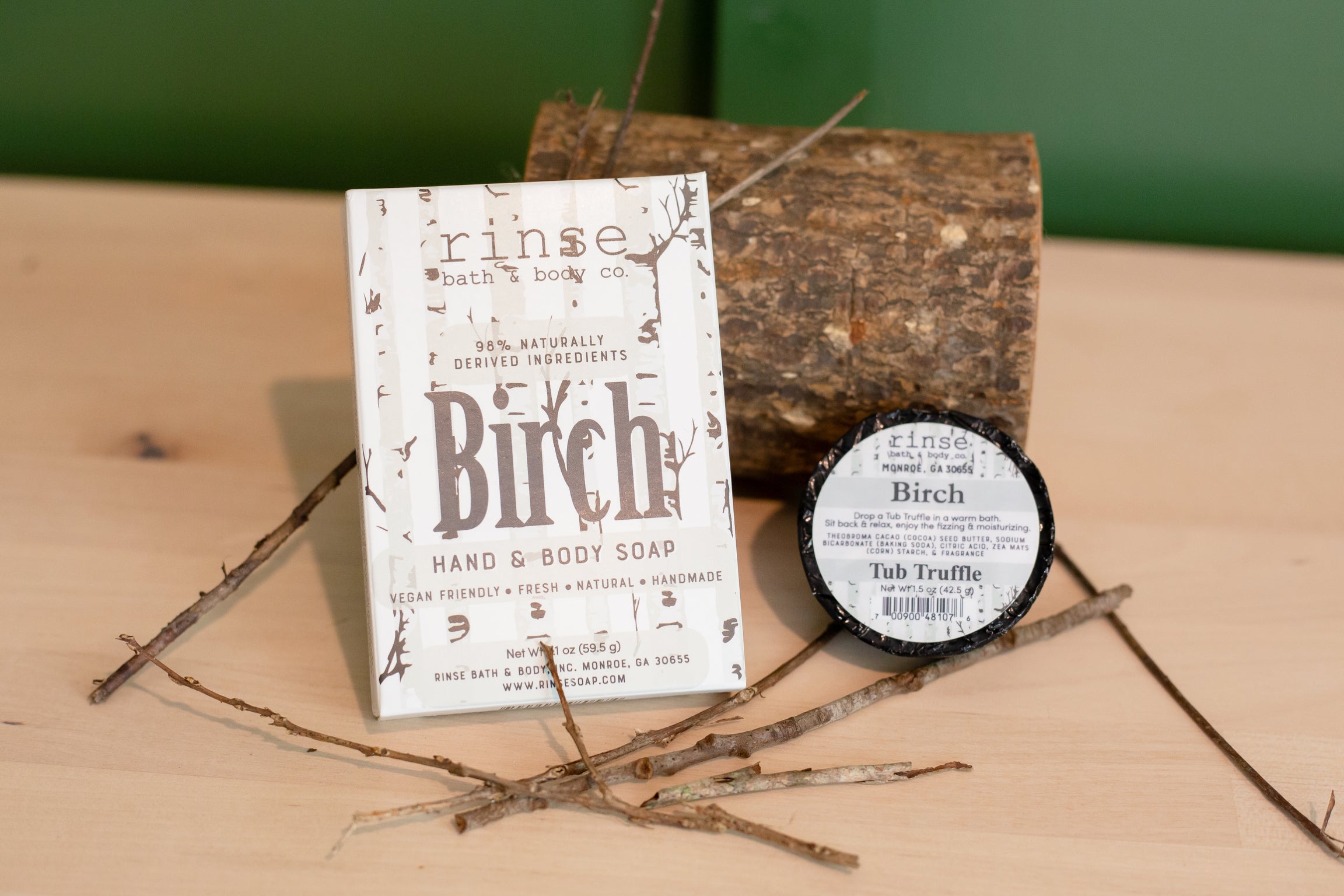 Rinse Birch hand and body soap beside birch logs and twigs on wood