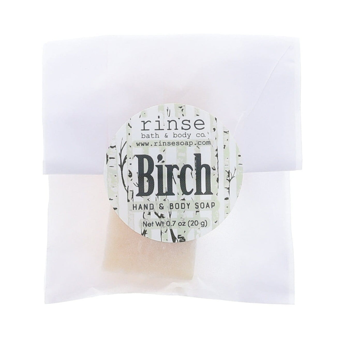 Birch soap slice peeks through glassine with birch-bark sticker — sample bar on clean bright white