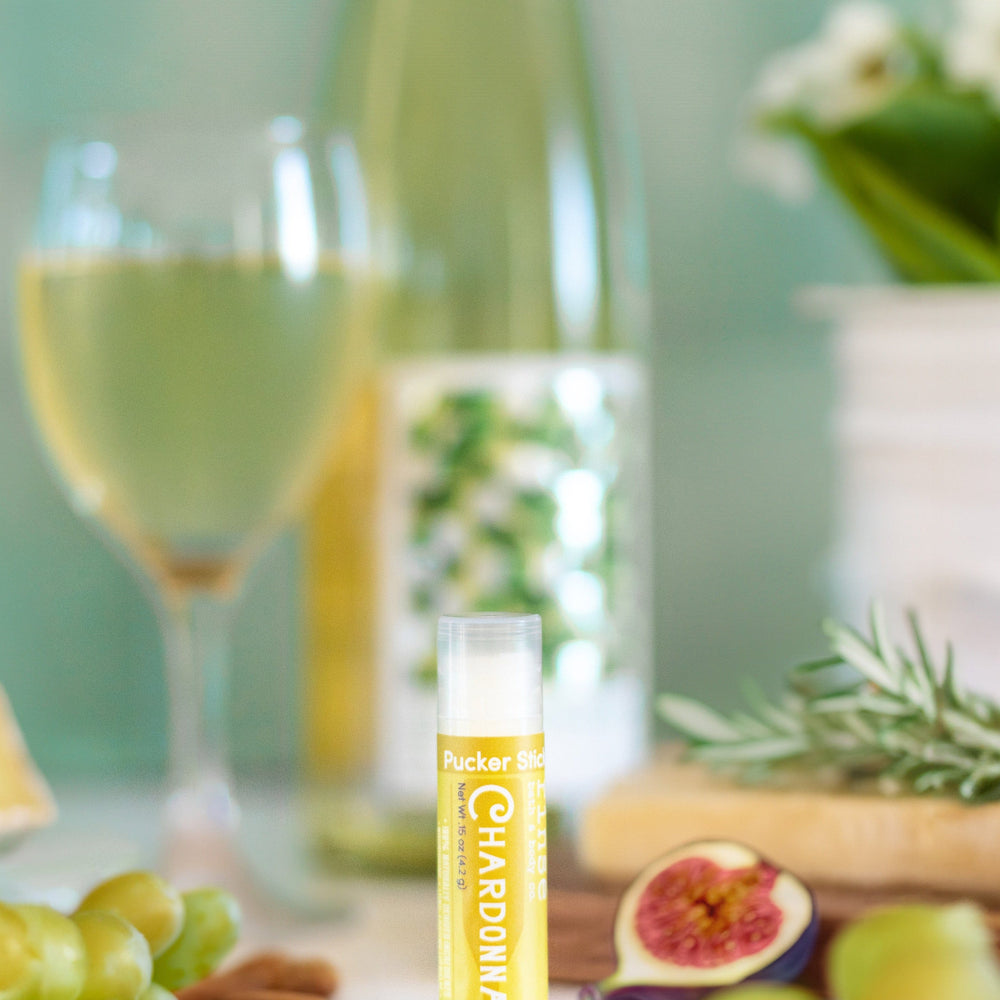 Chardonnay lip balm beside a glass of white wine