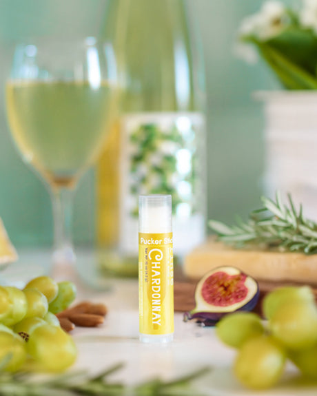 Chardonnay lip balm beside a glass of white wine