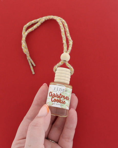 Christmas Cookie car diffuser held in hand on red — 4:5 hero