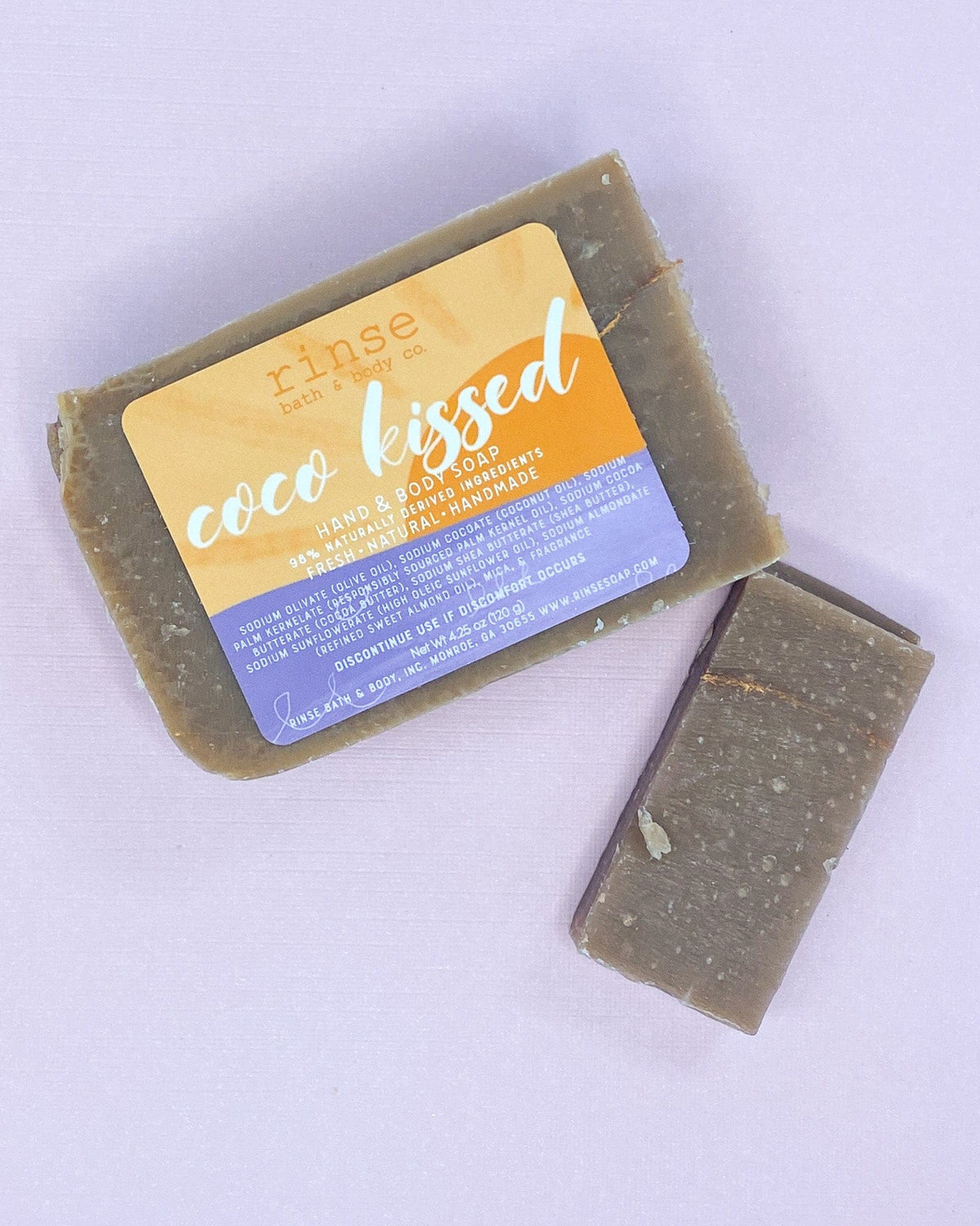Full Coco Kissed bar and thin slice on pale lavender — speckled taupe soap in soft flat-lay light