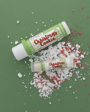 Christmas Cookie Skin Stick and Pucker Stick lifestyle on forest green — sugar crystals and bakery sprinkles