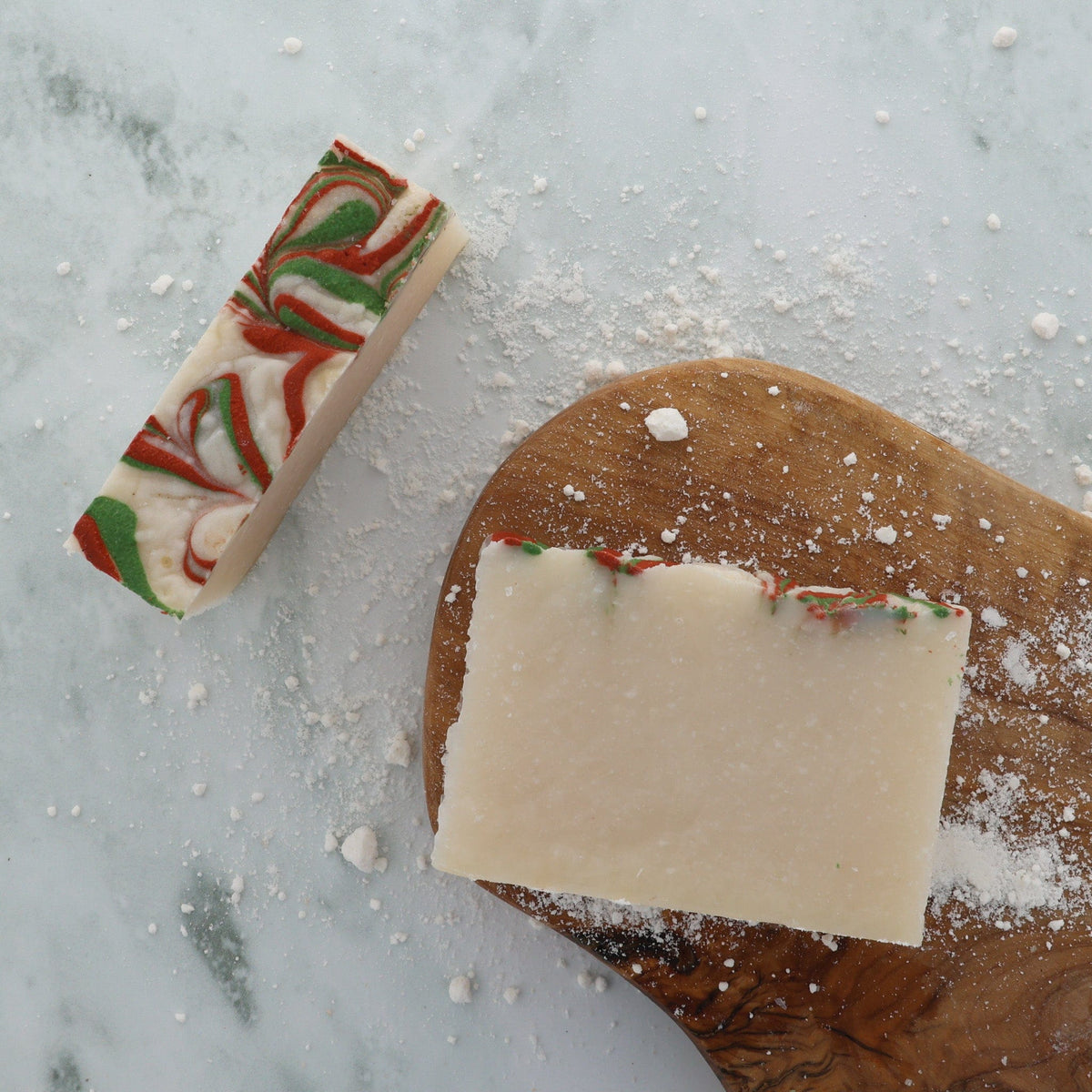 Christmas Cookie soap stylized on grey marble — red-green swirl dusted with white powder