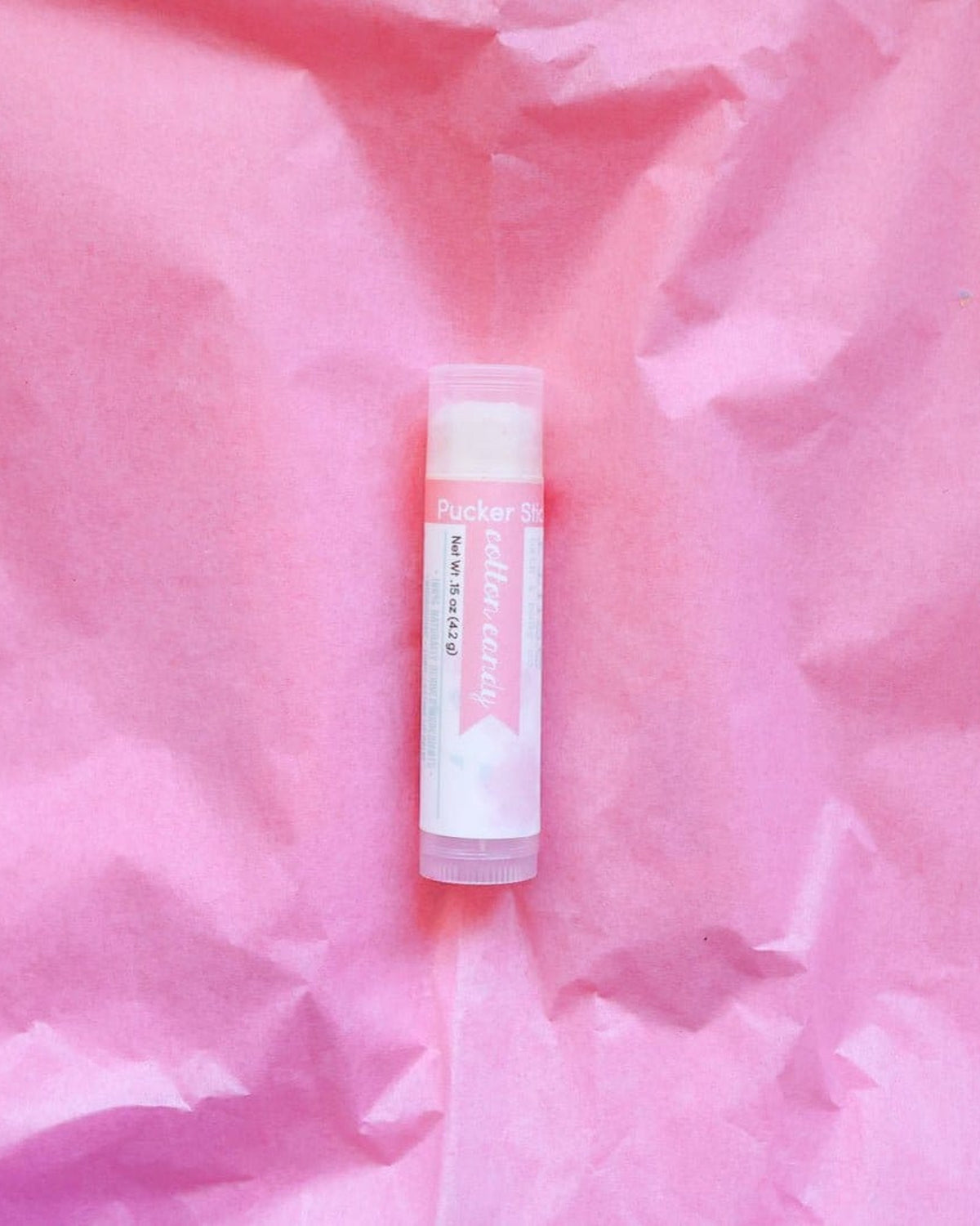 Cotton Candy Pucker Stick standing in crinkled neon-pink tissue — playful candy glow under bright light