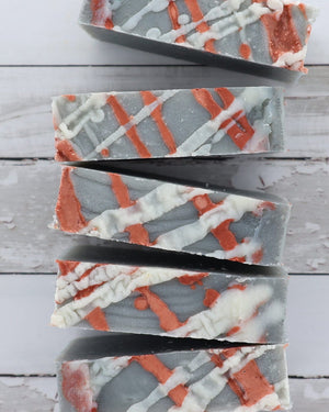 Flannel bar soap with its red plaid label and charcoal swirl running through the pour. Rinse Bath & Body Co.