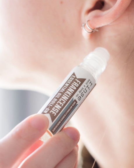 Frankincense essential oil roll-on in its glass bottle with steel rollerball — pre-diluted and ready for pulse points. Rinse Bath & Body Co.