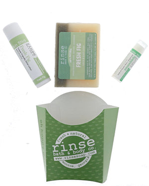 The Fresh Fig set laid out flat — bar soap, Fresh Fig solid lotion skin stick and Speppermint lip balm above the green printed carton. Rinse Bath & Body Co.