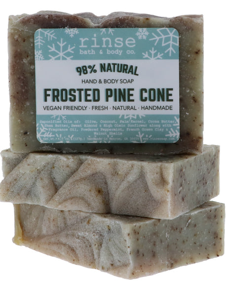 Frosted Pine Cone soap stylized flat lay — speckled sage bars with snowflake labels stacked on bright white