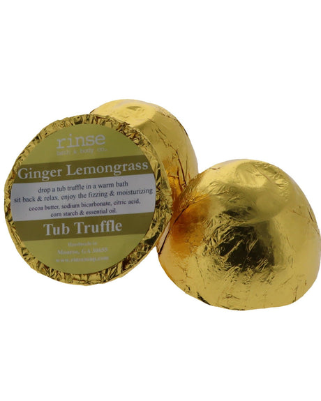 A gold foil-wrapped Ginger Lemongrass Tub Truffle beside a second one cut open to show the cocoa butter dome, on white — sharp ginger, warm lemongrass. Rinse Bath & Body Co.