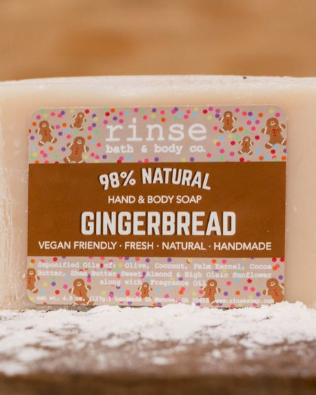 Gingerbread soap in-use on dark wood dusted with flour — warm kitchen lifestyle holding the bar