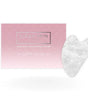 A white quartz gua sha stone on its pink backing card — a hand-polished facial tool used over a facial oil. Rinse Bath & Body Co.