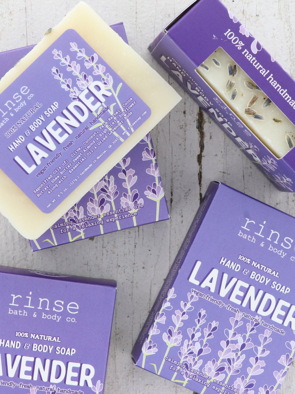 Lavender soap bars and purple cartons rest on light rustic wood — floral packaging in clean daylight