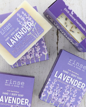 Lavender soap bars and purple cartons rest on light rustic wood — floral packaging in clean daylight