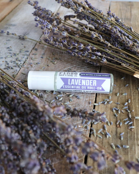 The Lavender Essential Oil Roll-On lying among bundles of dried lavender on weathered wood