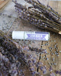 The Lavender Essential Oil Roll-On lying among bundles of dried lavender on weathered wood
