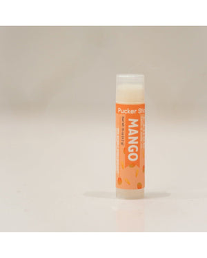 Mango Pucker Stick upright — saturated orange mango label and clear cap on bright white