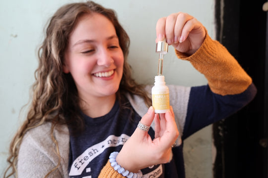 woman holding Marula oil dropped about to apply the product to her face