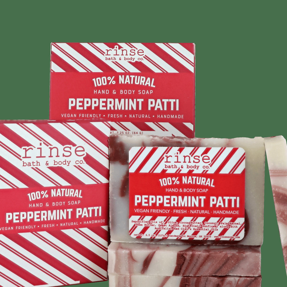 Peppermint Patti mini soaps before candy-cane striped cartons — cream and chocolate swirls on deep forest green
