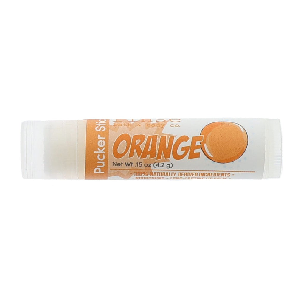 Orange Pucker Stick lying on bright white — orange fruit graphic and clear-capped creamy balm in studio light