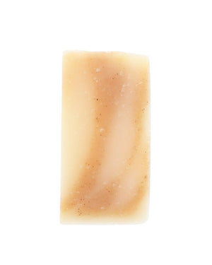 Bare Golden Glow soap slice stands upright — ivory bar with speckled tan swirls on stark white