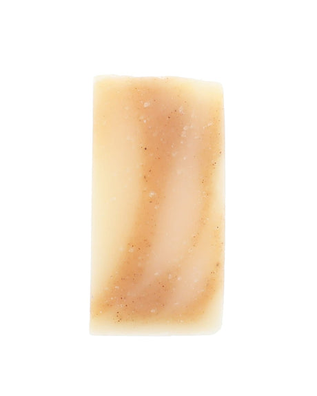 Bare Golden Glow soap slice stands upright — ivory bar with speckled tan swirls on stark white