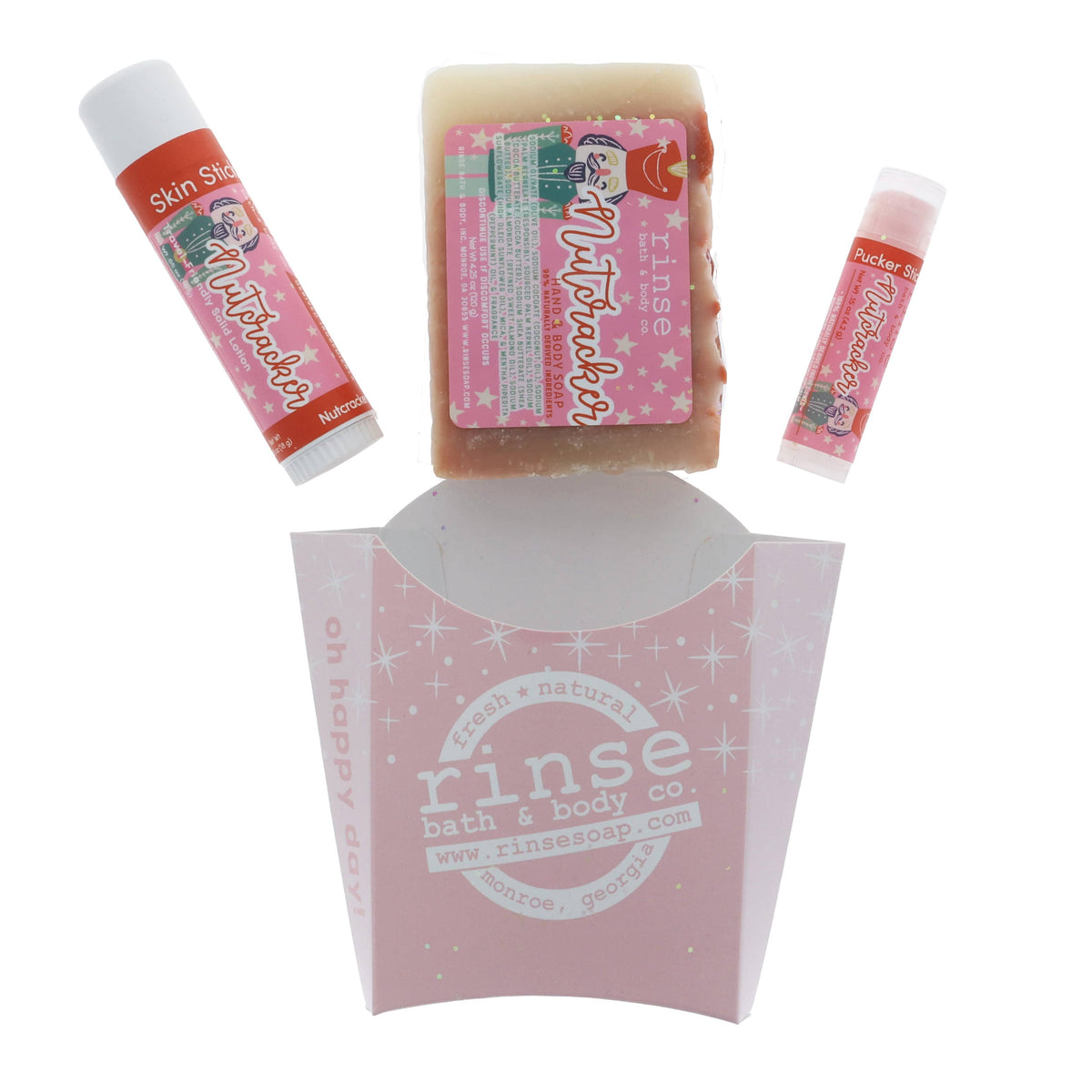 Nutcracker holiday trio arranged above pale pink sparkle carton — handmade soap and solid sticks catching soft studio light