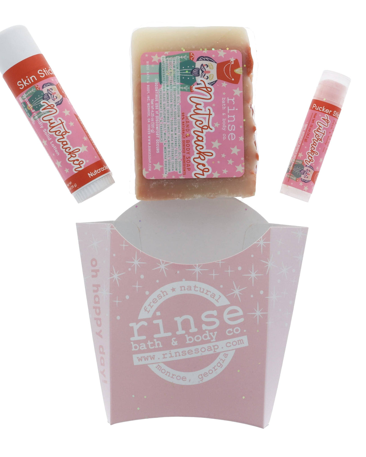 The Nutcracker set laid out flat — bar soap, solid lotion skin stick and lip balm above the pink sparkle carton. Rinse Bath & Body Co.