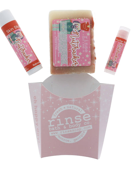 The Nutcracker set laid out flat — bar soap, solid lotion skin stick and lip balm above the pink sparkle carton. Rinse Bath & Body Co.