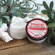 Open Peppermint Patti Body Spread on weathered wood — holly berries and soft cotton tufts around the jar