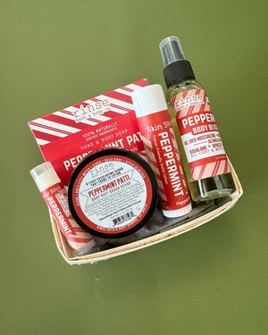 Peppermint Patti travel gift set flat lay on green — wooden berry till with candy-stripe mini soap, skin stick, lip balm, Body Bliss oil, and Body Buff
