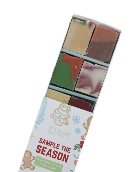Open Sample the Season sleeve angled on white revealing six colorful half bars — speckled cream, two-tone brown, green-red swirl, and plum marble soaps