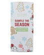 Sample the Season box standing on bright white — gingerbread, tree, snowflake, and berry illustrations with red SAMPLE THE SEASON lettering