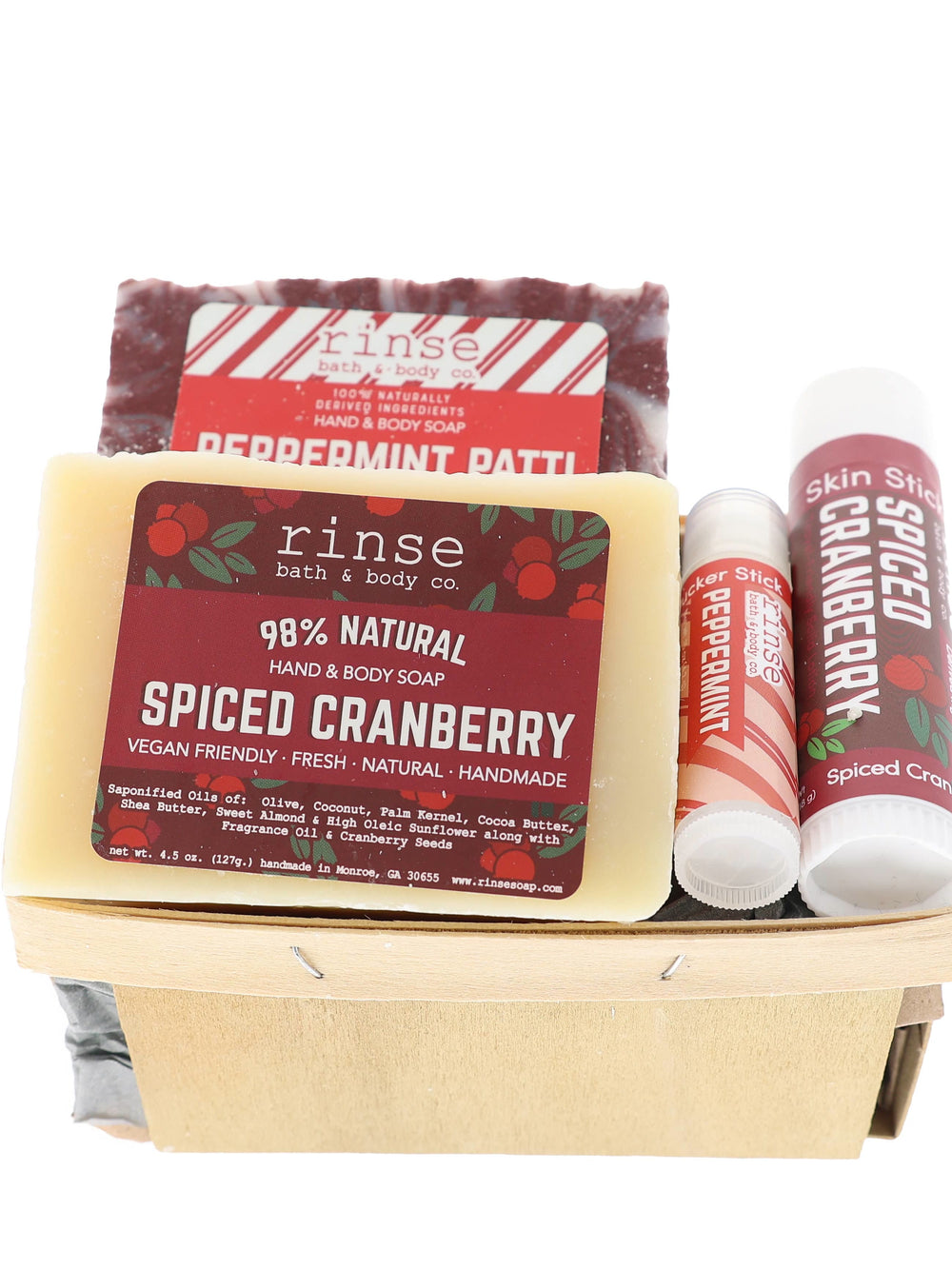 Holiday soap-and-stick duo filling a pale wood berry basket — cranberry and candy-cane labels on white