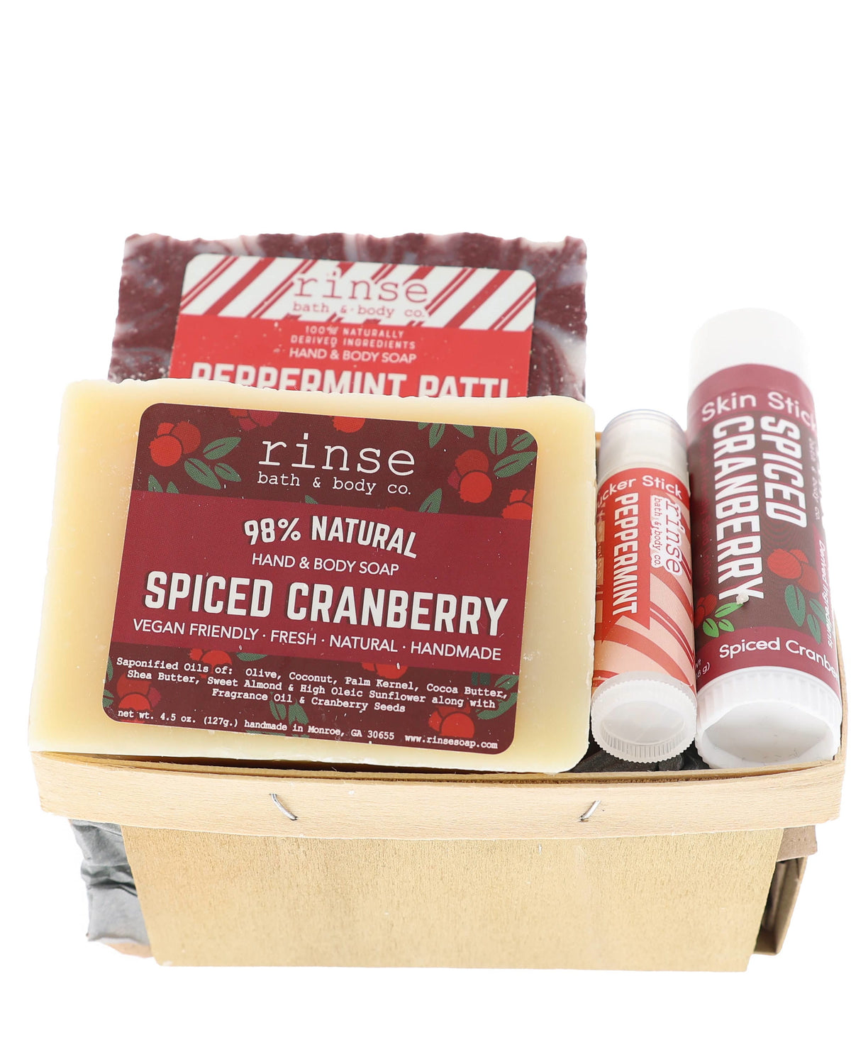 Holiday soap-and-stick duo filling a pale wood berry basket — cranberry and candy-cane labels on white