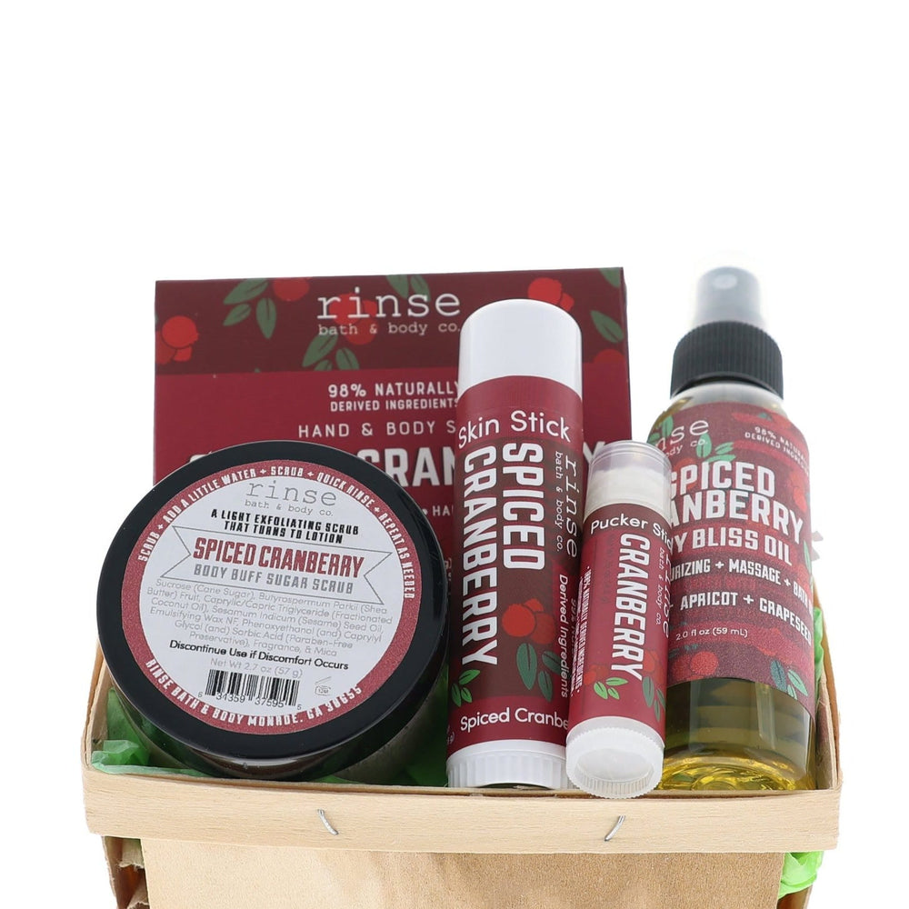 Spiced Cranberry travel set nestled in a wood berry till — green crinkle fill and burgundy labels on bright white